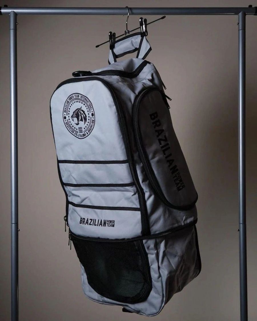 Grey Brazilian Power Team training backpack hanging on a rail.